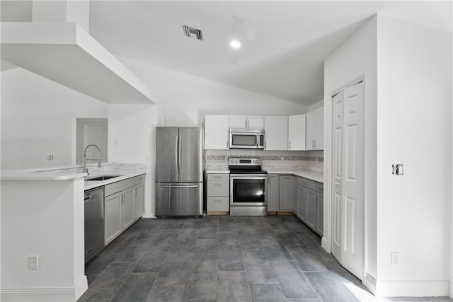 kitchen with stainless steel appliances, gray cabinetry, tasteful backsplash, vaulted ceiling, and sink