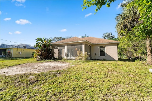 back of property with a sunroom and a lawn