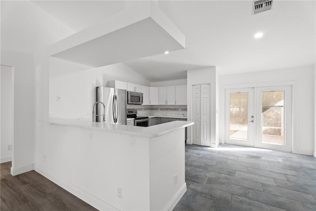 kitchen with white cabinetry, kitchen peninsula, appliances with stainless steel finishes, decorative backsplash, and french doors