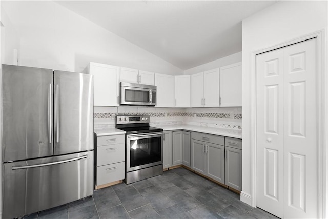 kitchen featuring lofted ceiling, stainless steel appliances, gray cabinetry, and decorative backsplash