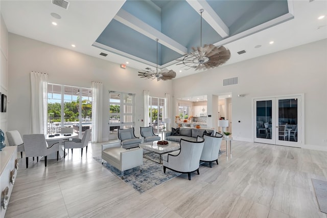 living room with ceiling fan, plenty of natural light, and a high ceiling