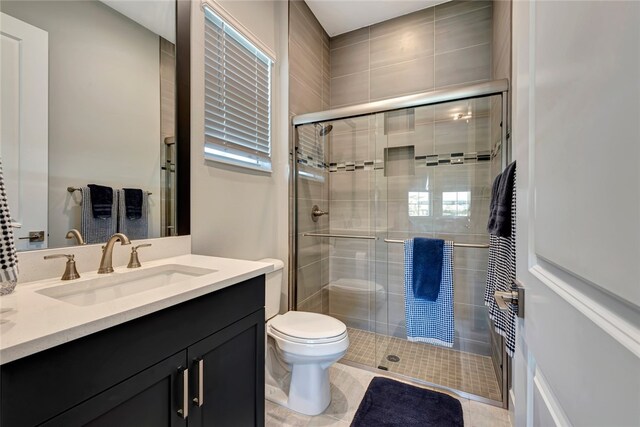 bathroom with tile patterned flooring, vanity, toilet, and a shower with shower door