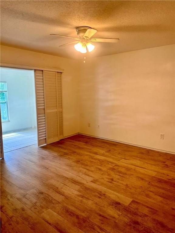 unfurnished room with a textured ceiling, hardwood / wood-style floors, and ceiling fan