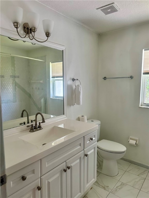 bathroom with toilet, a chandelier, a textured ceiling, vanity, and walk in shower