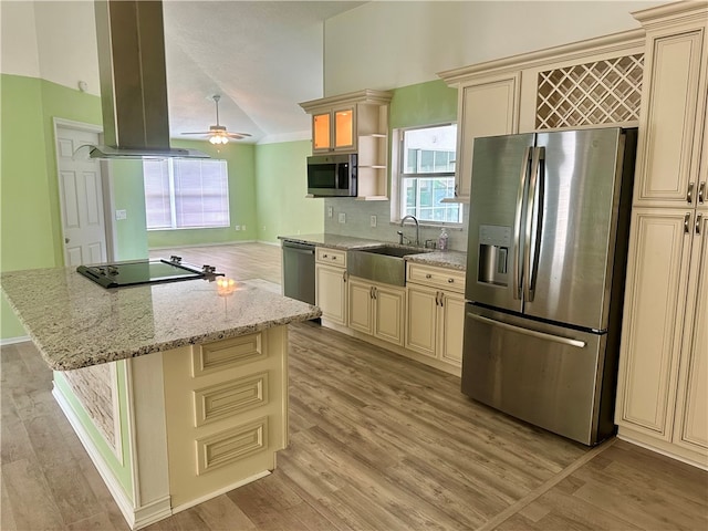 kitchen featuring light stone counters, light wood-type flooring, appliances with stainless steel finishes, sink, and a center island