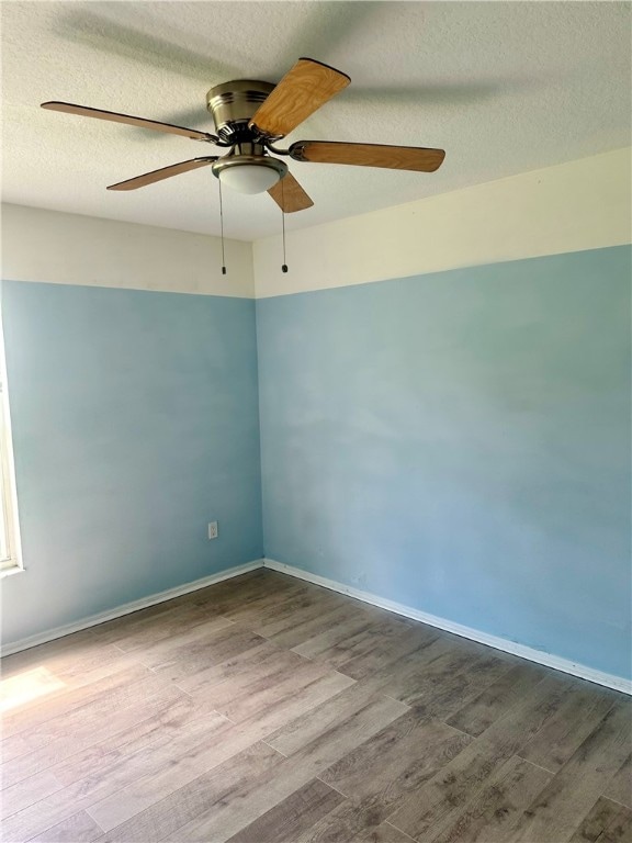 empty room with a textured ceiling, hardwood / wood-style flooring, and ceiling fan