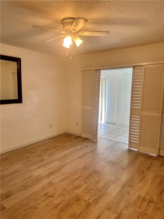 interior space featuring a closet, a textured ceiling, ceiling fan, and light hardwood / wood-style flooring