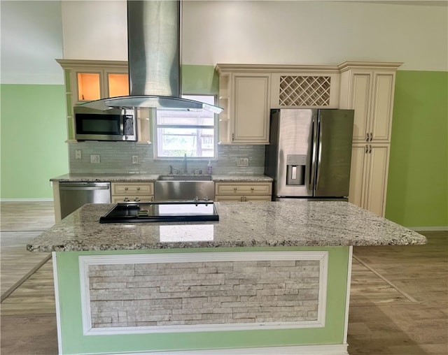 kitchen with stainless steel appliances, island exhaust hood, light stone countertops, and backsplash