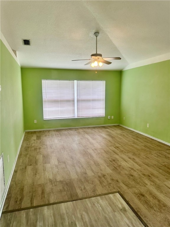 empty room with a textured ceiling, wood-type flooring, and ceiling fan