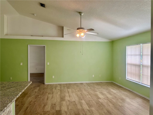 unfurnished room featuring a textured ceiling, light hardwood / wood-style floors, ceiling fan, and vaulted ceiling