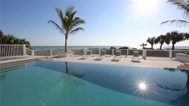 view of pool with a patio area and a water view