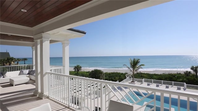 balcony with a view of the beach, a water view, and an outdoor hangout area