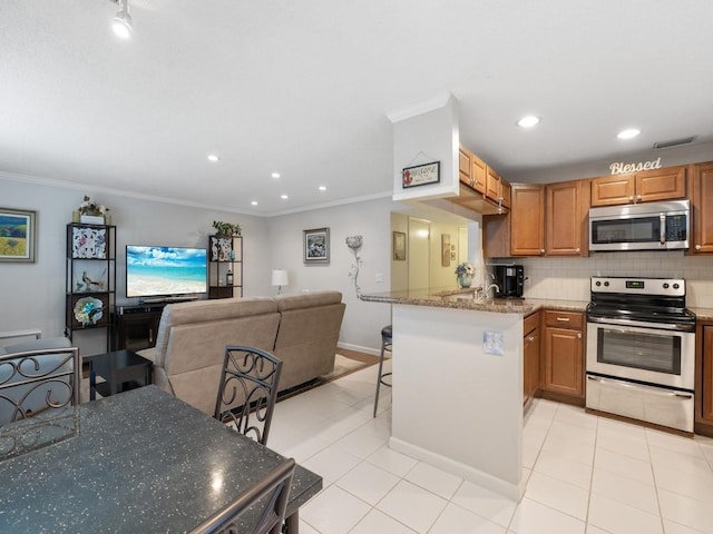 2800 Indian River Blvd Unit J1, Vero Beach, FL 32960 - kitchen with stainless steel appliances, a breakfast bar area, ornamental molding, decorative backsplash, and light tile patterned floors
