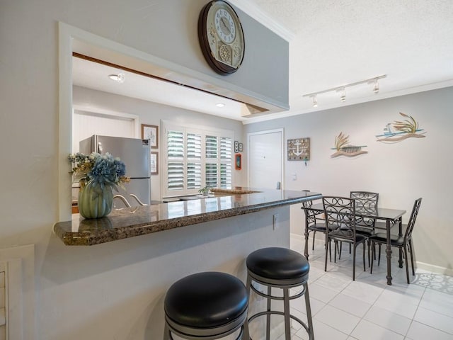 2800 Indian River Blvd Unit J1, Vero Beach, FL 32960 - kitchen featuring freestanding refrigerator, light tile patterned floors, track lighting, baseboards, and a peninsula