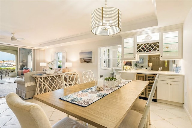 dining area featuring light tile patterned floors, wet bar, a raised ceiling, and crown molding