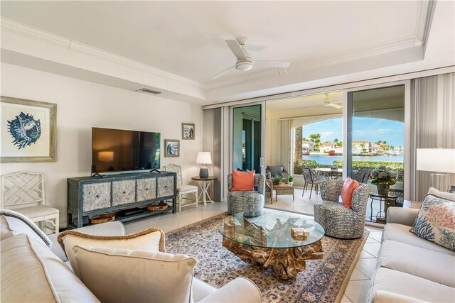 tiled living area featuring ornamental molding, a raised ceiling, visible vents, and ceiling fan