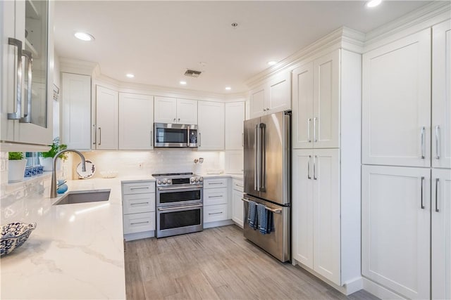 kitchen with visible vents, appliances with stainless steel finishes, light stone counters, white cabinetry, and a sink