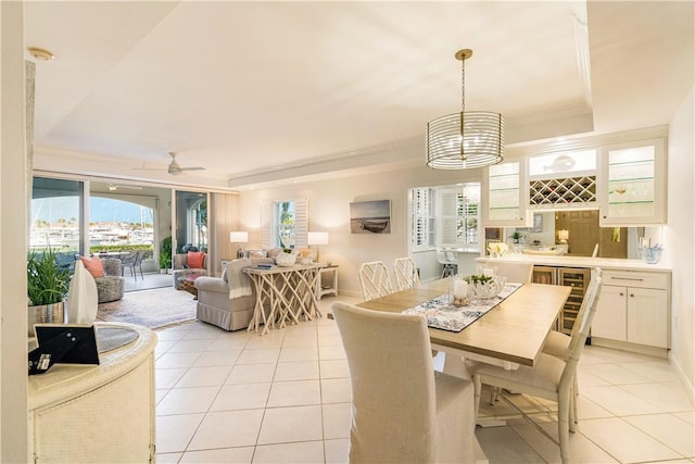 dining space featuring a tray ceiling, ornamental molding, indoor wet bar, and light tile patterned flooring