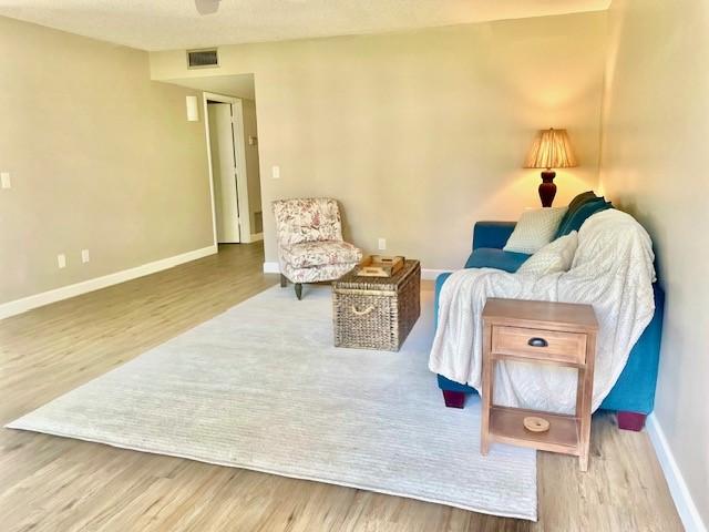 living area featuring visible vents, wood finished floors, and baseboards