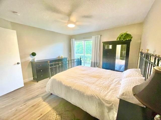 bedroom with access to exterior, a textured ceiling, wood finished floors, baseboards, and ceiling fan