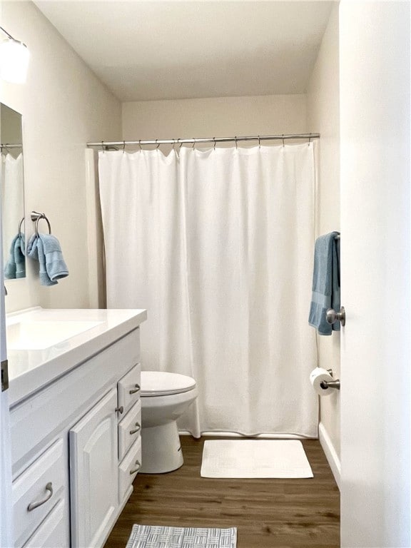 bathroom with toilet, vanity, a shower with shower curtain, and wood finished floors