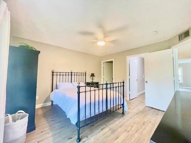 bedroom featuring a ceiling fan, wood finished floors, visible vents, and baseboards