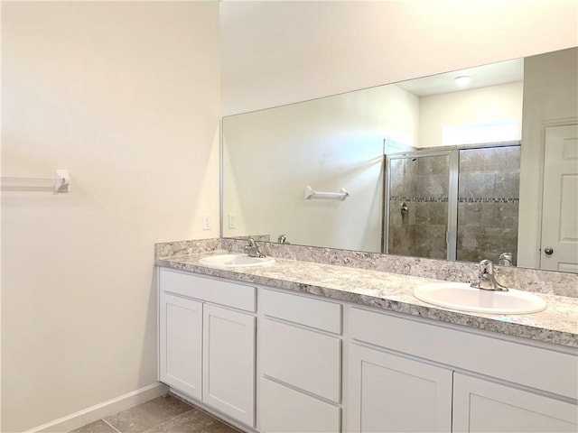 bathroom with a stall shower, a sink, baseboards, and double vanity