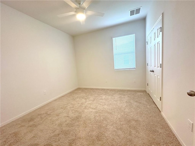 spare room with carpet floors, ceiling fan, visible vents, and baseboards