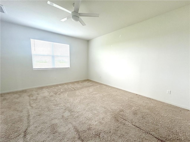 carpeted empty room with visible vents, a ceiling fan, and baseboards