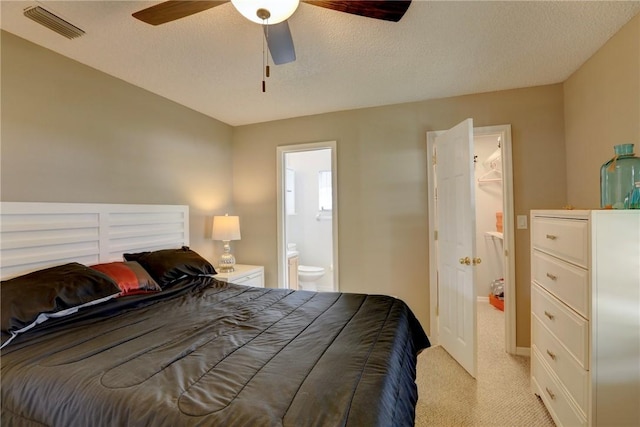 bedroom featuring ceiling fan, connected bathroom, a textured ceiling, visible vents, and light carpet