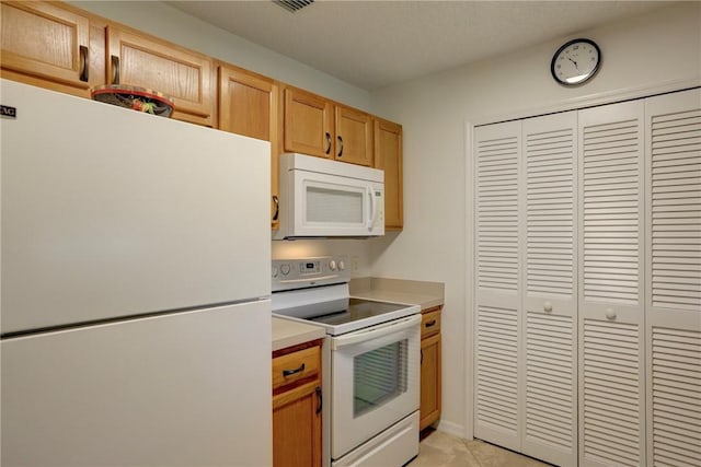kitchen with light tile patterned floors, white appliances, light brown cabinetry, visible vents, and light countertops