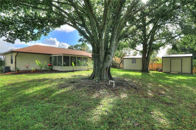 view of yard with an outdoor structure, a sunroom, a storage shed, central AC, and fence