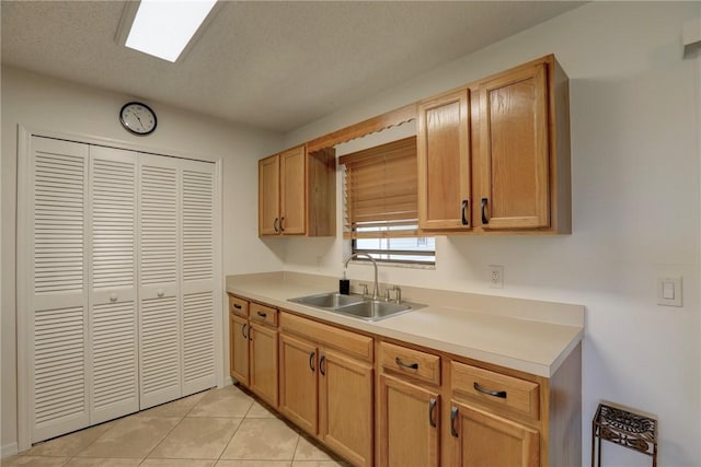 kitchen featuring light tile patterned floors, light countertops, and a sink