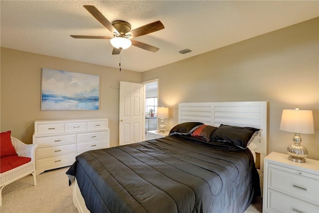 bedroom with light carpet, visible vents, a textured ceiling, and a ceiling fan