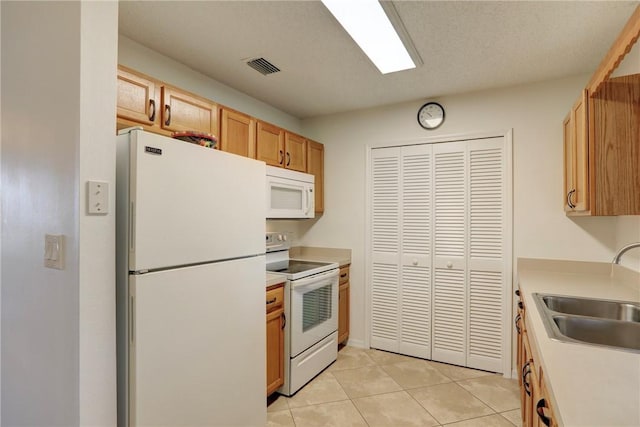 kitchen with visible vents, a sink, light countertops, white appliances, and light tile patterned flooring
