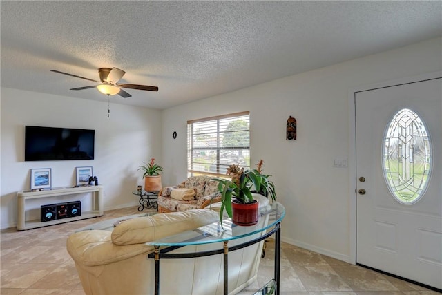 living room with ceiling fan, baseboards, and a textured ceiling