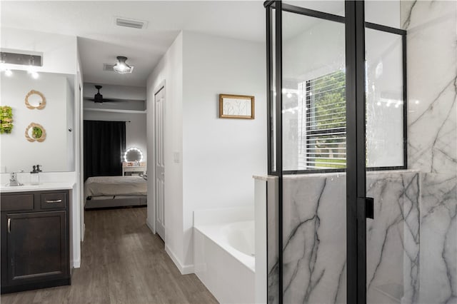 bathroom with hardwood / wood-style floors, a tub to relax in, vanity, and ceiling fan