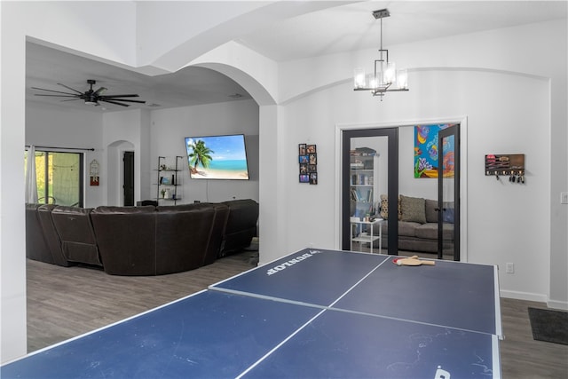 playroom with ceiling fan with notable chandelier and dark hardwood / wood-style flooring