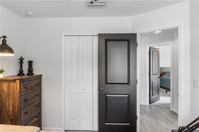 bedroom featuring a closet, light wood-type flooring, and a textured ceiling