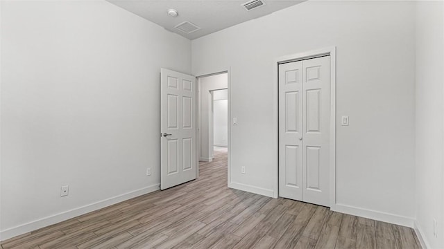 unfurnished bedroom with light hardwood / wood-style floors and a closet