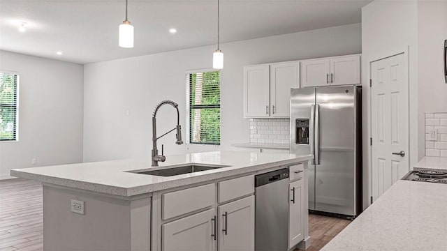 kitchen with appliances with stainless steel finishes, pendant lighting, white cabinetry, sink, and backsplash