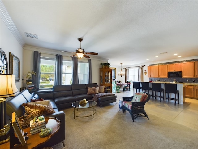 living room with ceiling fan with notable chandelier, light tile patterned flooring, and crown molding