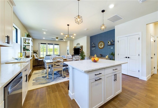 kitchen with white cabinets, light stone countertops, stainless steel dishwasher, and hanging light fixtures