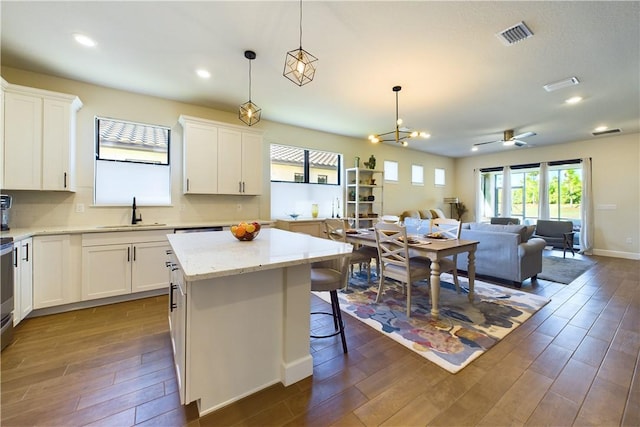 kitchen with white cabinets, a center island, sink, and hanging light fixtures