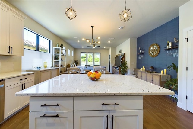 kitchen with dark wood-type flooring, white cabinets, hanging light fixtures, a notable chandelier, and a kitchen island