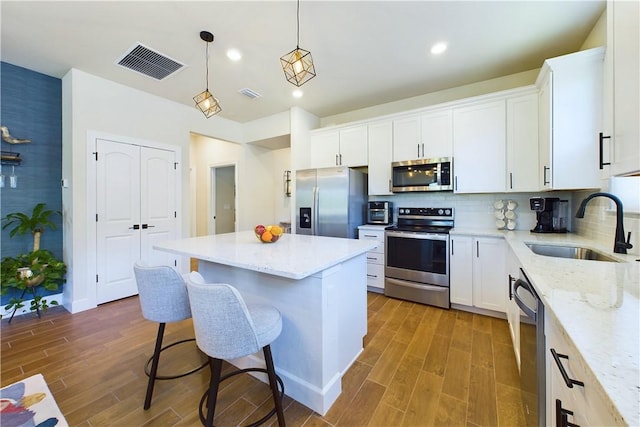 kitchen featuring stainless steel appliances, a kitchen island, white cabinetry, and sink