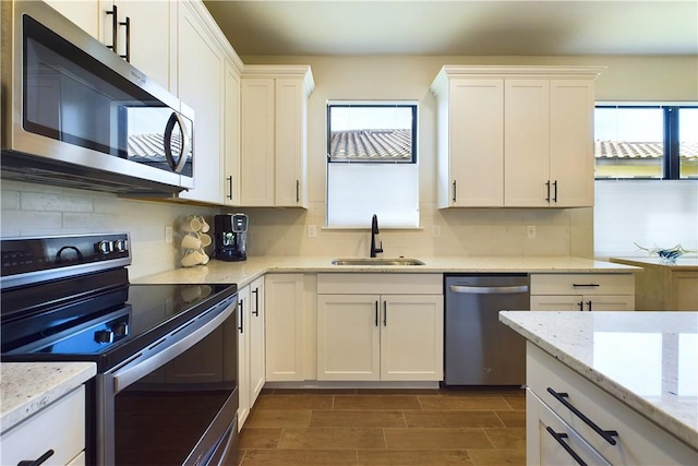 kitchen featuring white cabinets, stainless steel appliances, light stone counters, and sink