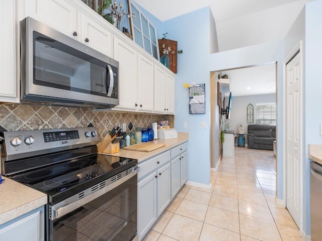 kitchen with tasteful backsplash, stainless steel appliances, light tile patterned floors, and white cabinets