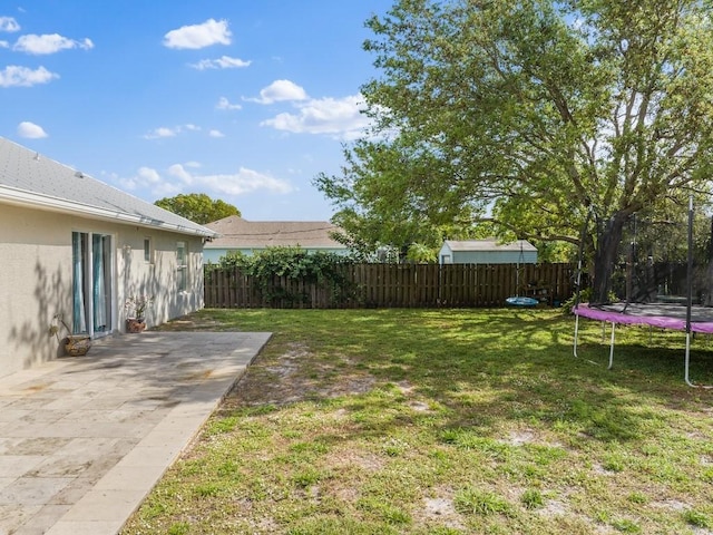 view of yard with a trampoline and a patio area