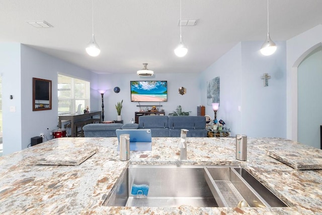 kitchen featuring light stone countertops, sink, and pendant lighting